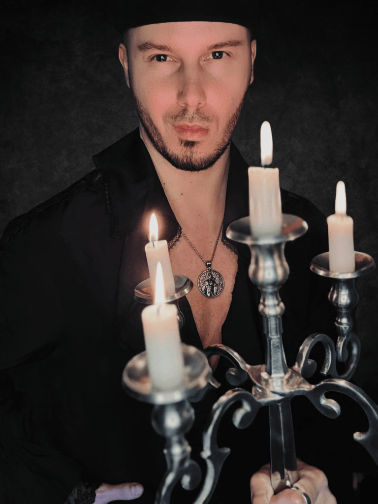 tarocista ubrany w żabot trzymający kandelabr na szarym tle